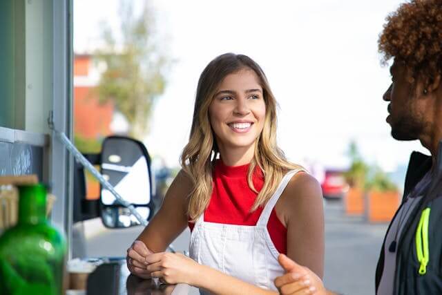 Young woman smiling while talking to a customer outside a small business.