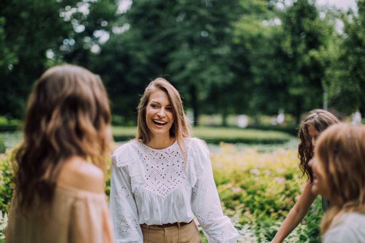 Three women standing together outdoors in a park, talking and smiling