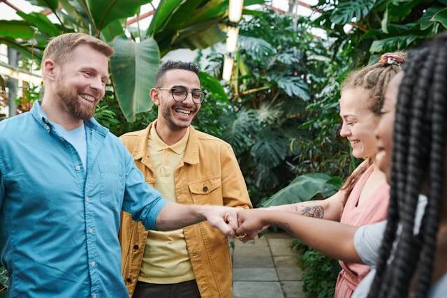 Group of adults greeting each other with a handshake in a relaxed, outdoor setting.