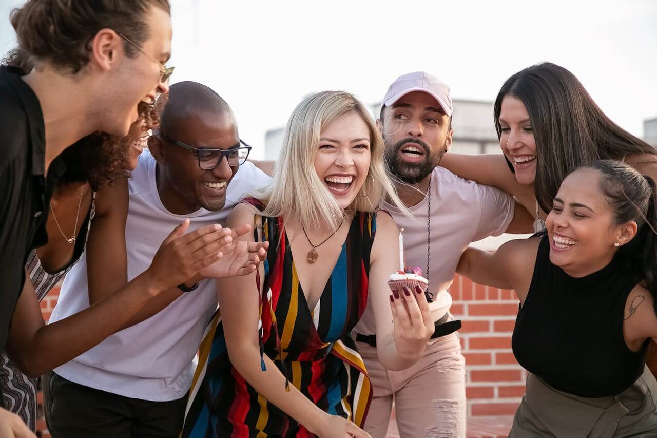 Group of people smiling and talking together outdoors.