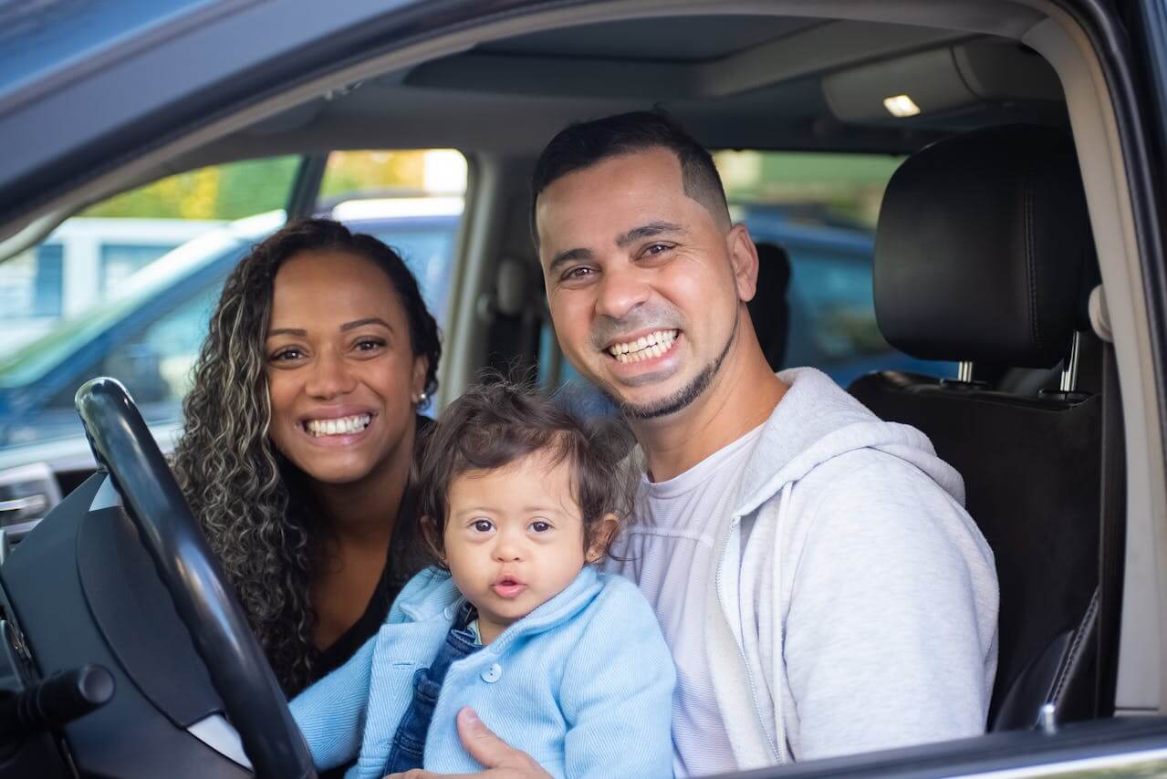 Smiling family sitting inside a car.